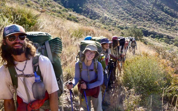 a group of people on a backpacking trip smile at the camera while on trail